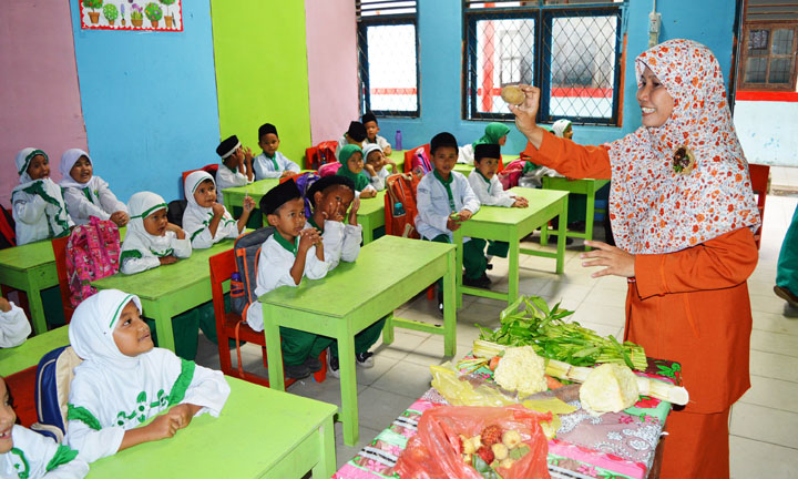 Nuriyawati tengah menerangkan pelajaran di depan kelas di MI Al Ikhlasiyah Palembang.